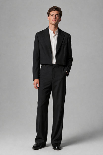 Front full-body view of a man wearing a Savile black 2-piece suit with a cropped peak-lapel jacket and wide-leg trousers