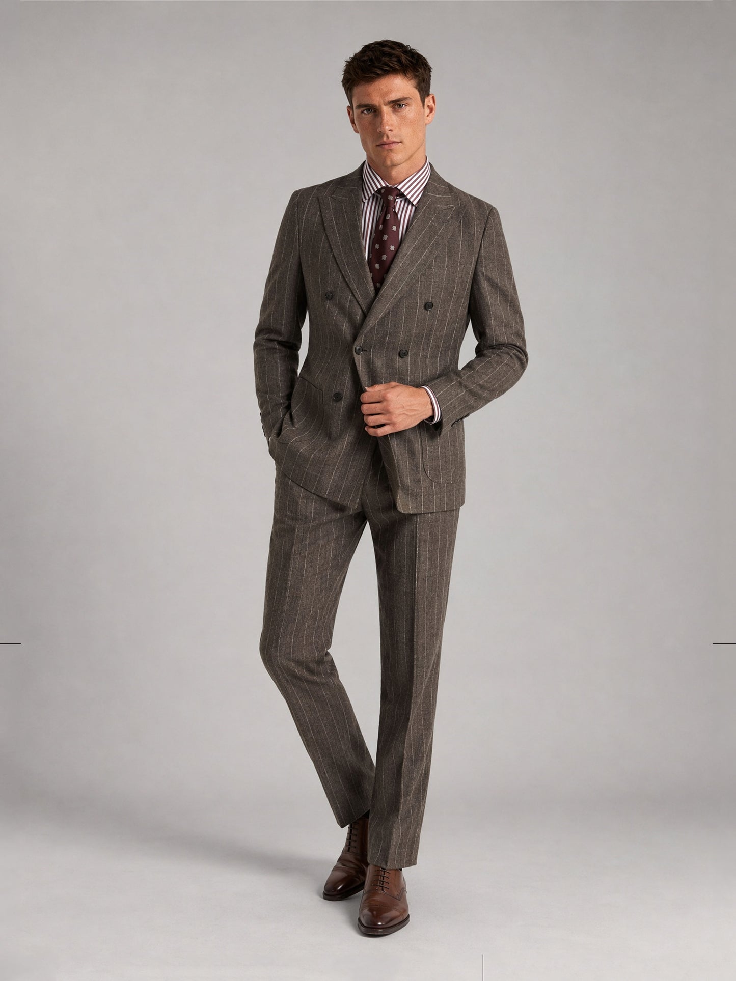 Savile GA0069 taupe chalk stripe double-breasted suit – full body three-quarter side pose, hands in pockets with brown oxford shoes and polka-dot tie