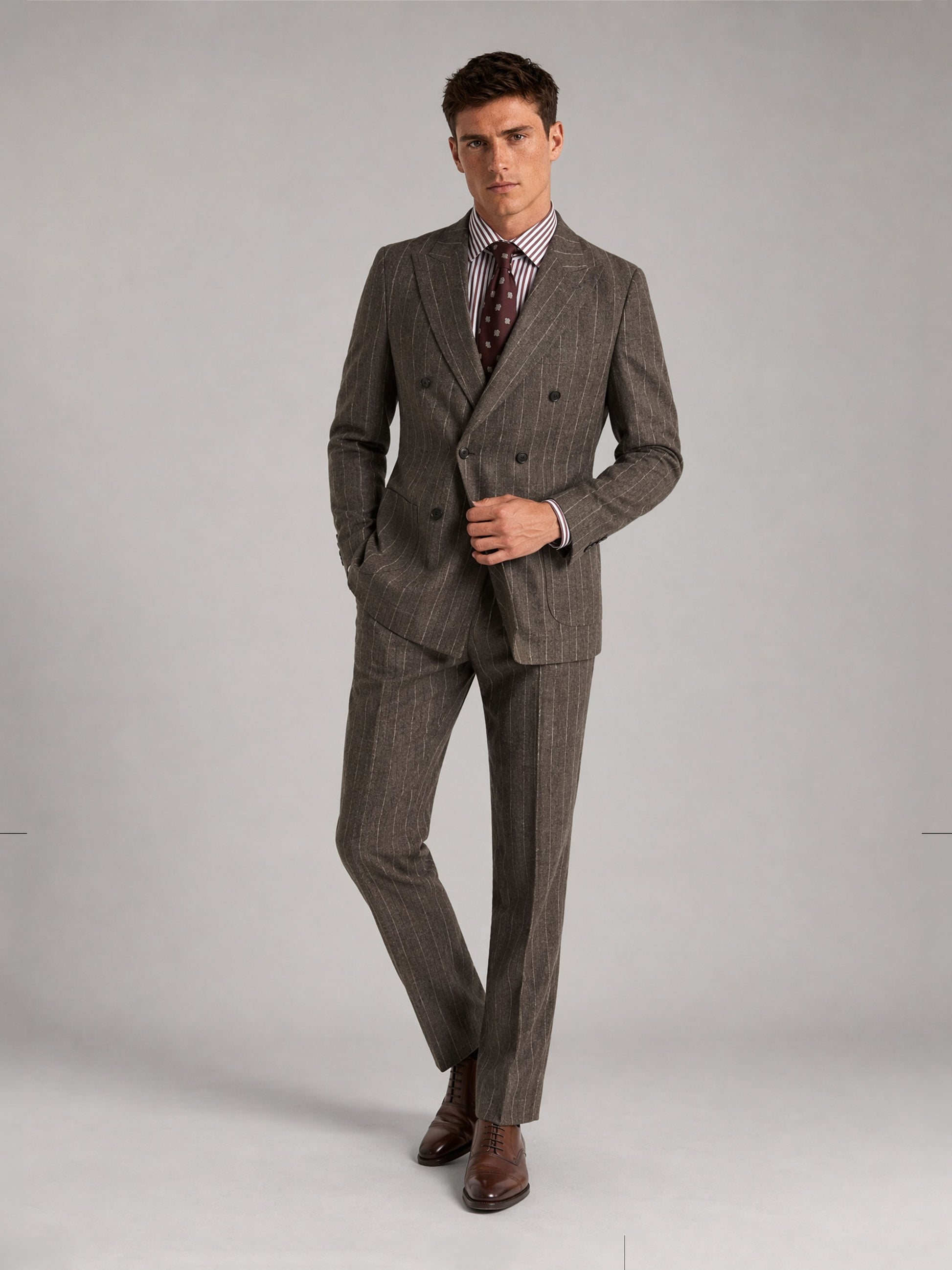 Savile GA0069 taupe chalk stripe double-breasted suit – full body three-quarter side pose, hands in pockets with brown oxford shoes and polka-dot tie