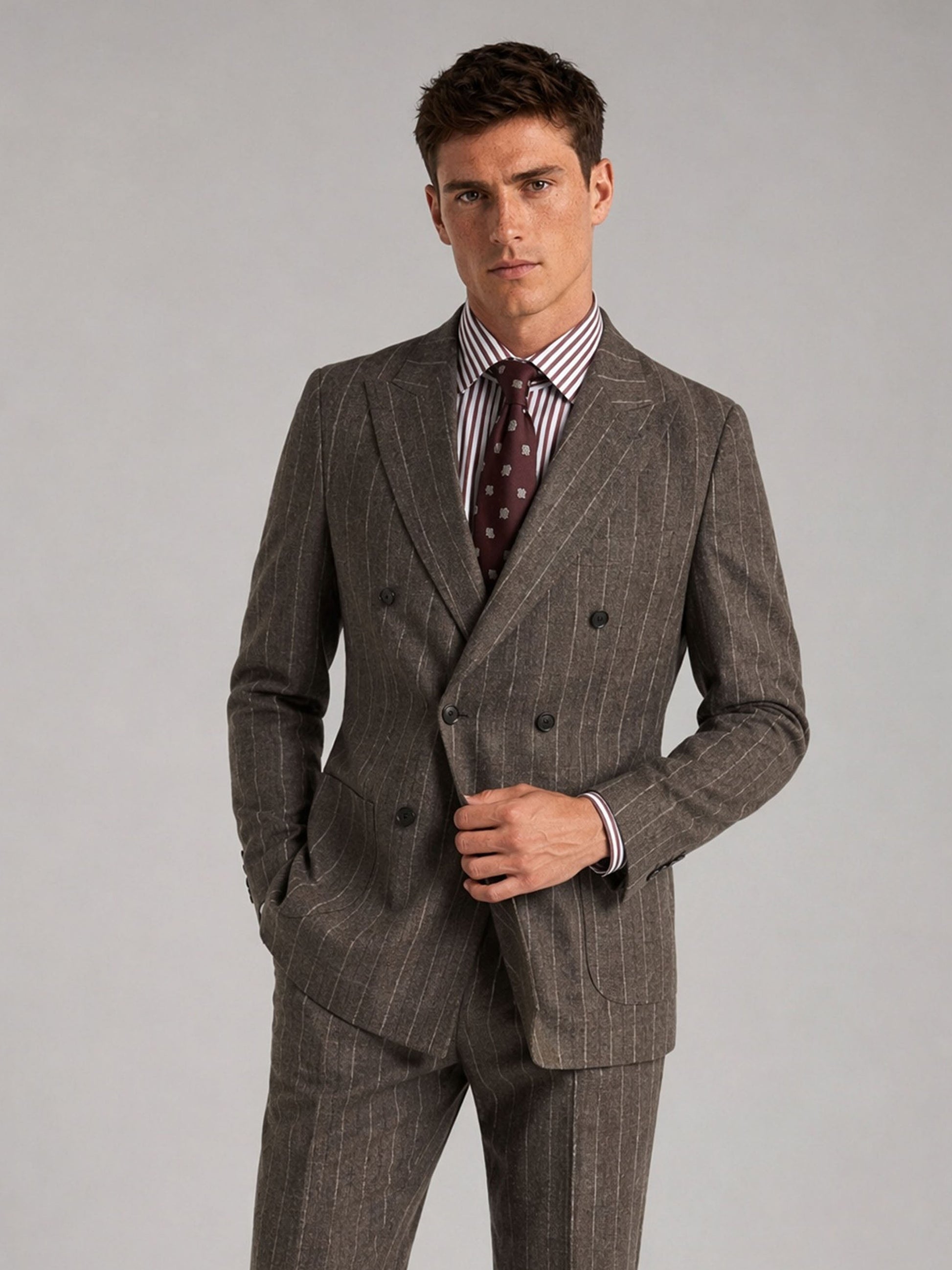 Savile GA0069 taupe chalk stripe 2-piece suit set – full body front view, hand touching lapel showing peak lapel silhouette and chalk stripe detail