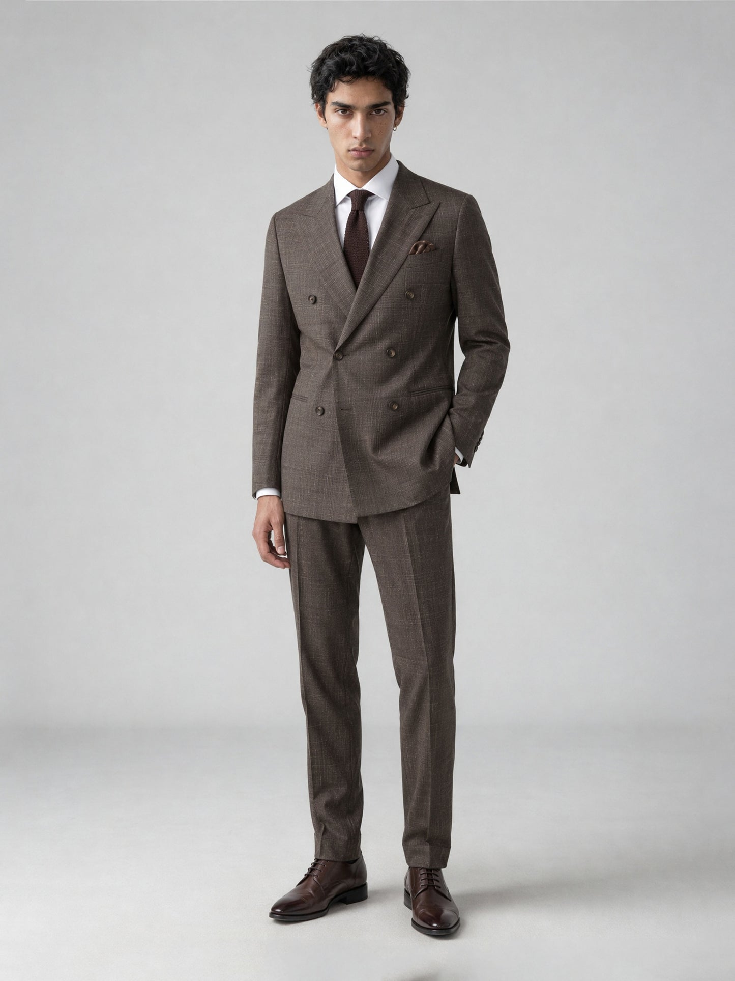 Savile GA0077 warm brown glen plaid double-breasted suit – full body front view, hand in pocket with dark brown brogue shoes and brown knit tie