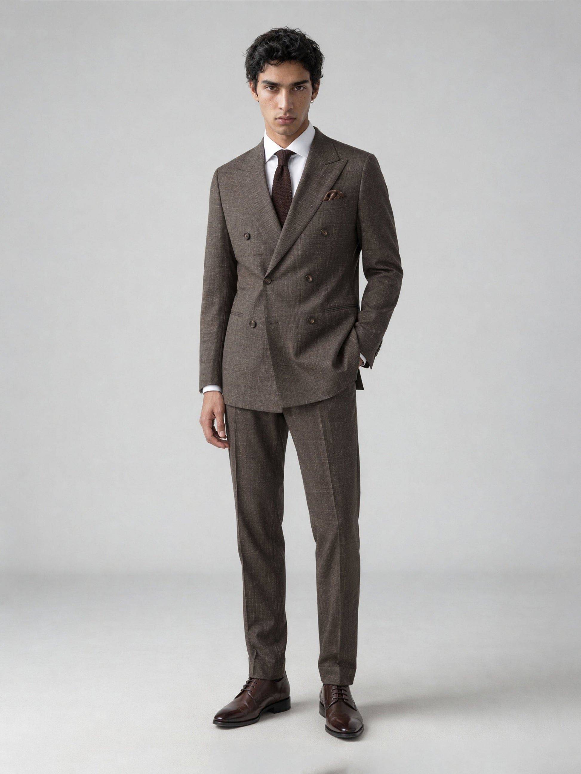Savile GA0077 warm brown glen plaid double-breasted suit – full body front view, hand in pocket with dark brown brogue shoes and brown knit tie