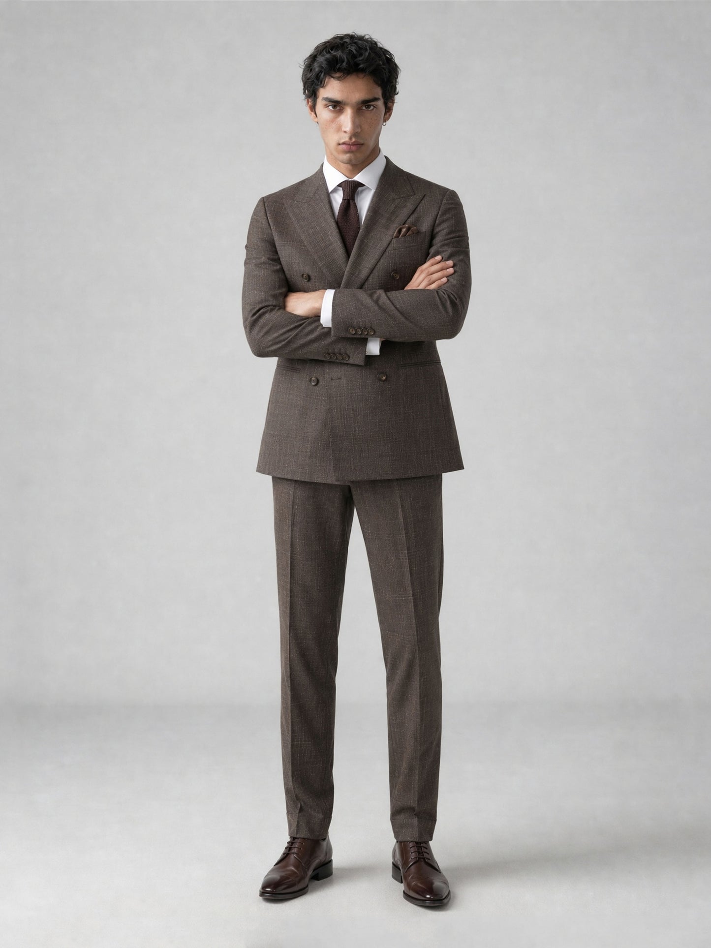 Savile GA0077 warm brown double-breasted suit – full body front view, arms crossed showing structured peak lapel silhouette and glen plaid fabric