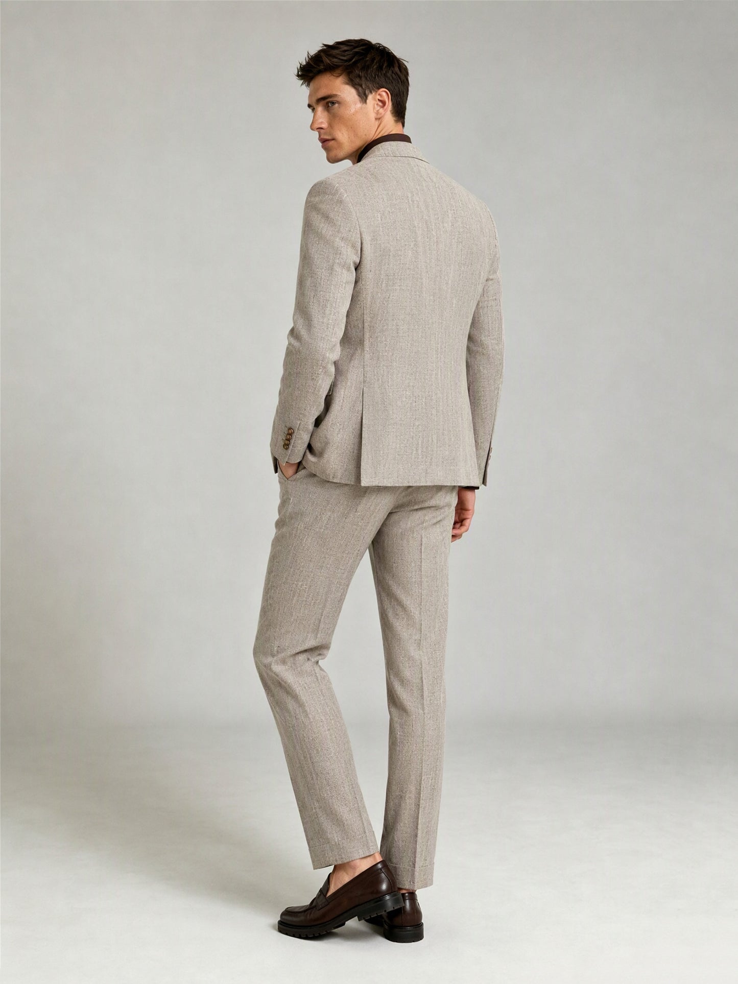 Savile GA0086 oatmeal windowpane check suit – full body front view, hand touching lapel showing Italian drape, peak lapel profile and slim trouser silhouette