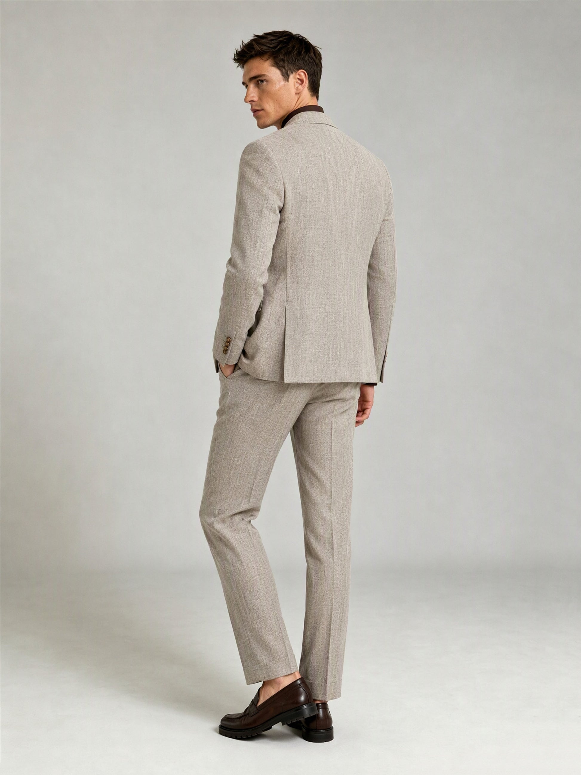 Savile GA0086 oatmeal windowpane check suit – full body front view, hand touching lapel showing Italian drape, peak lapel profile and slim trouser silhouette
