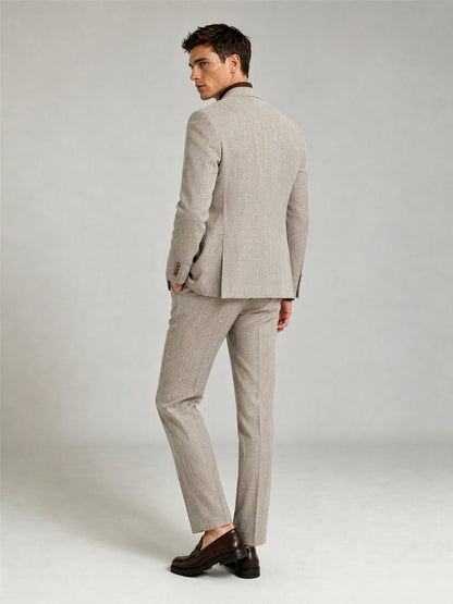 Savile GA0086 oatmeal windowpane check suit – full body front view, hand touching lapel showing Italian drape, peak lapel profile and slim trouser silhouette