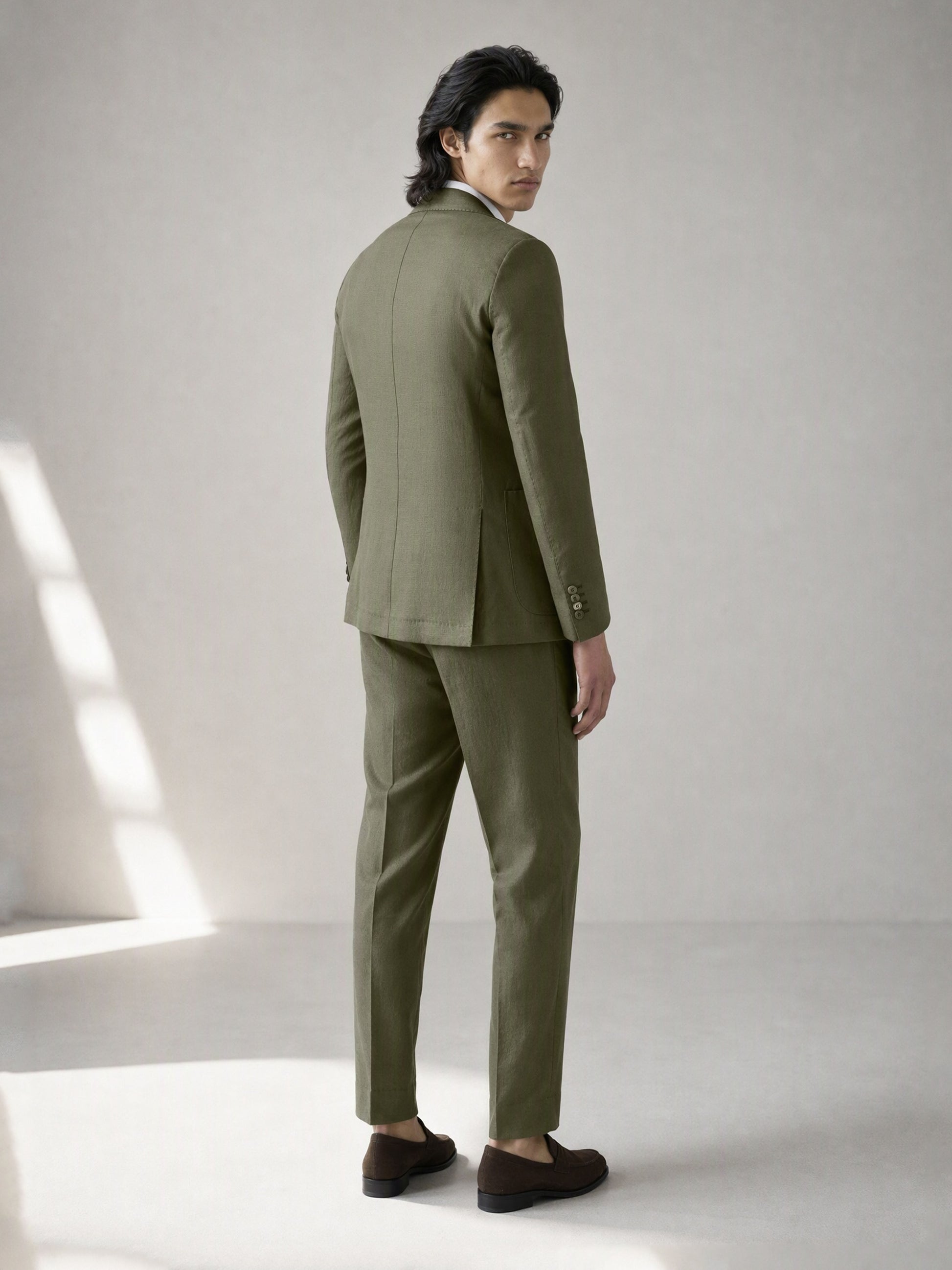 Savile olive green linen suit – back view, full length showing center vent and tapered trousers