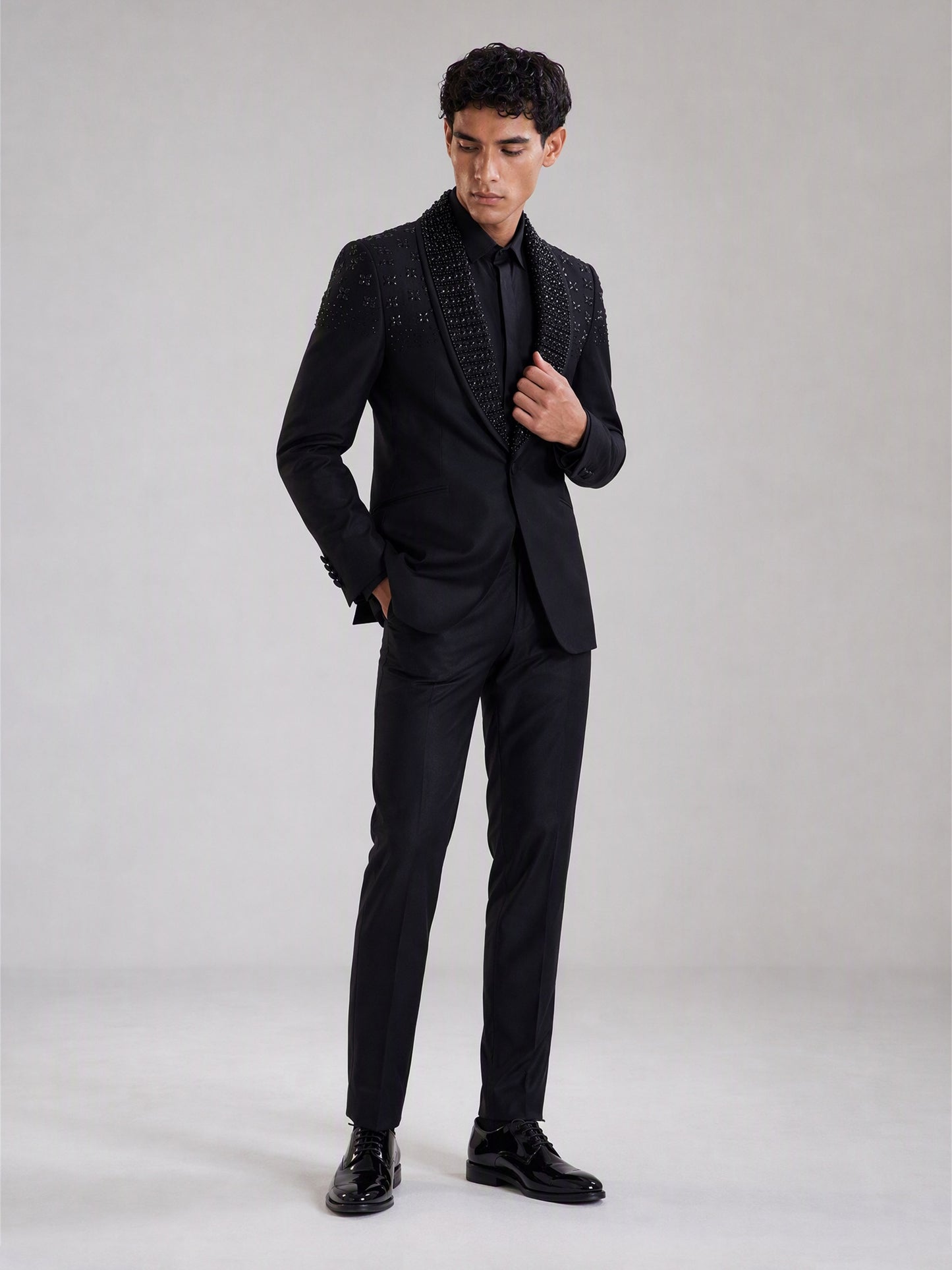 Savile black crystal shawl collar suit – full-length front view, hand at button showing crystal collar and clean body contrast