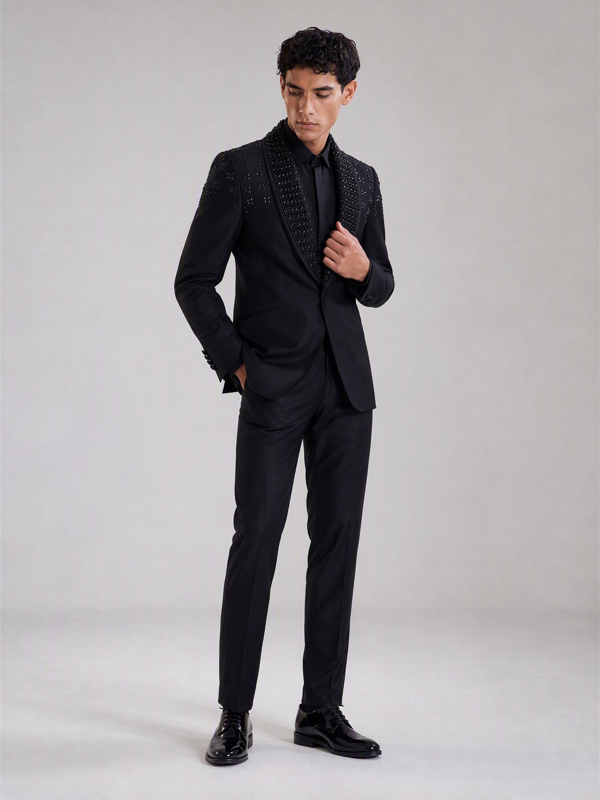 Savile black crystal shawl collar suit – full-length front view, hand at button showing crystal collar and clean body contrast