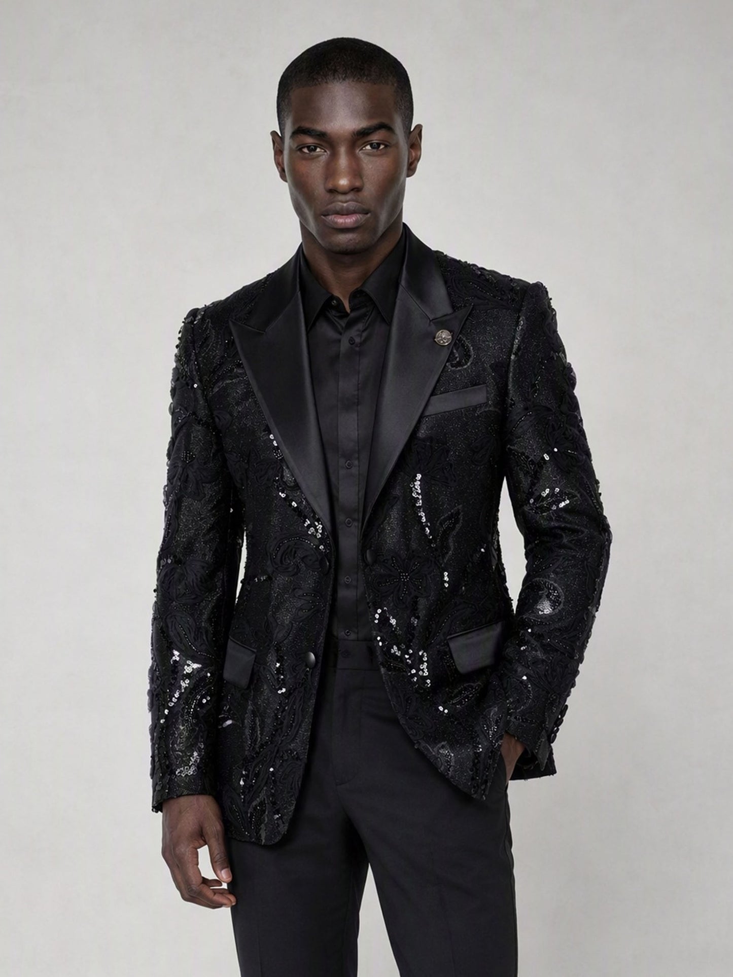 Savile black sequin floral suit – close-up upper body, black sequin botanical embroidery and satin peak lapel with silver brooch
