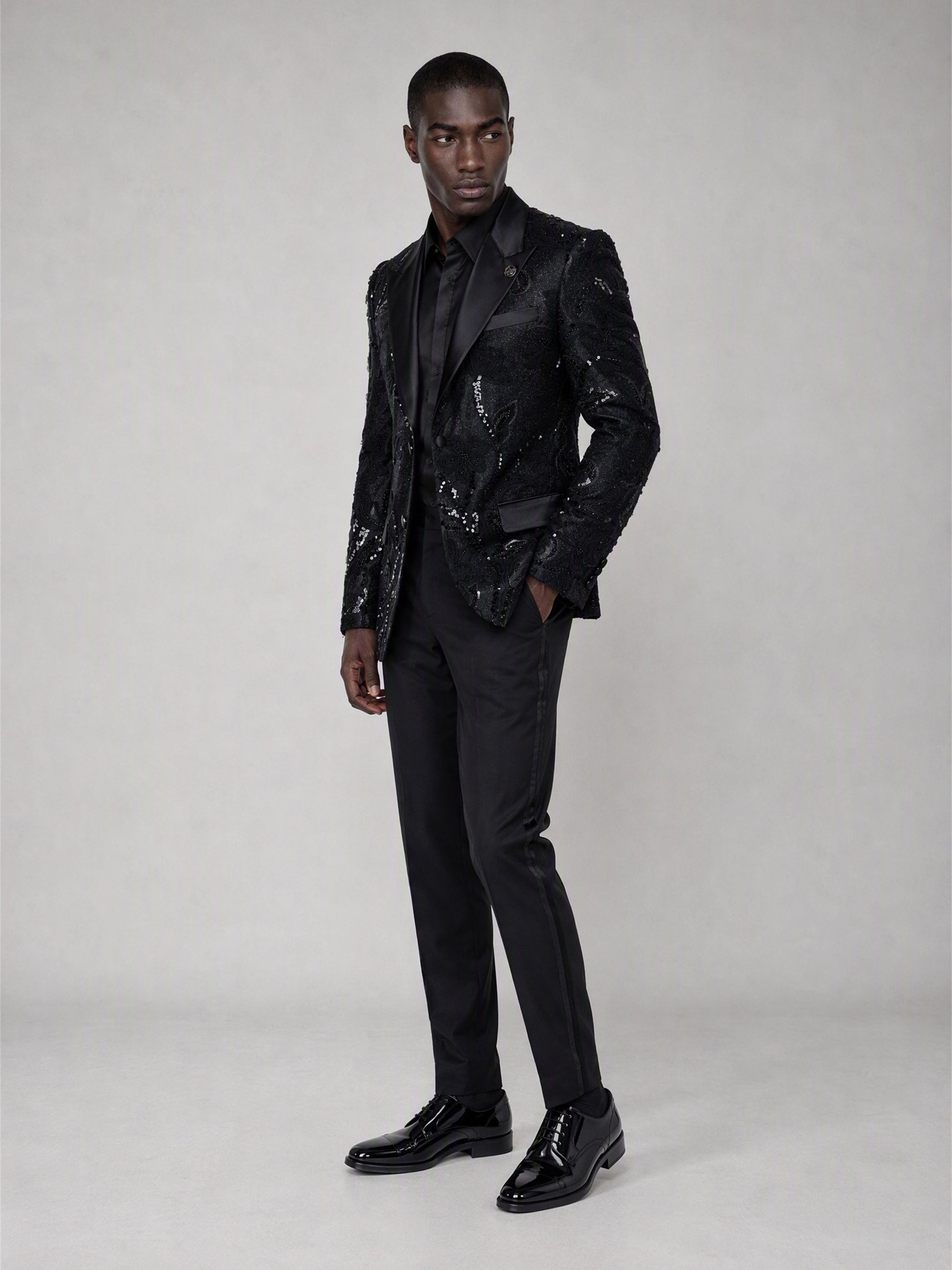 Savile black sequin floral suit – full-length side view, hand in pocket showing silhouette and sequin texture depth