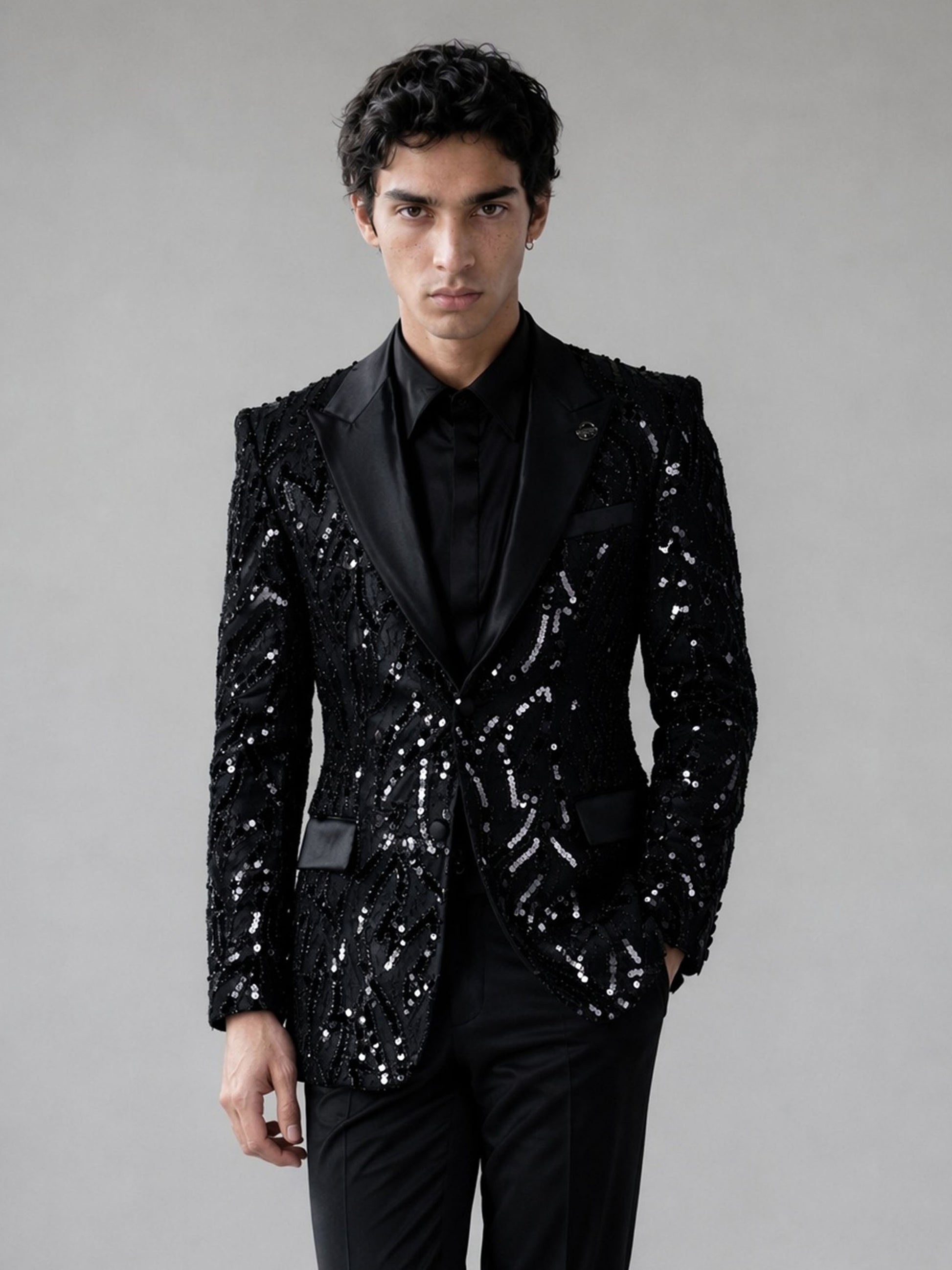 Savile black Art Deco sequin suit – close-up face and lapel, black medallion badge pin and satin peak lapel detail