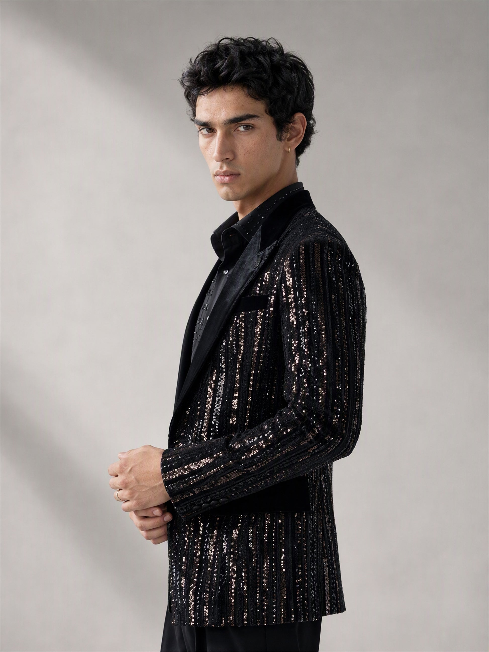 Savile black velvet sequin stripe suit – full-length side profile, hands clasped showing sequin stripe silhouette and black brogue oxfords