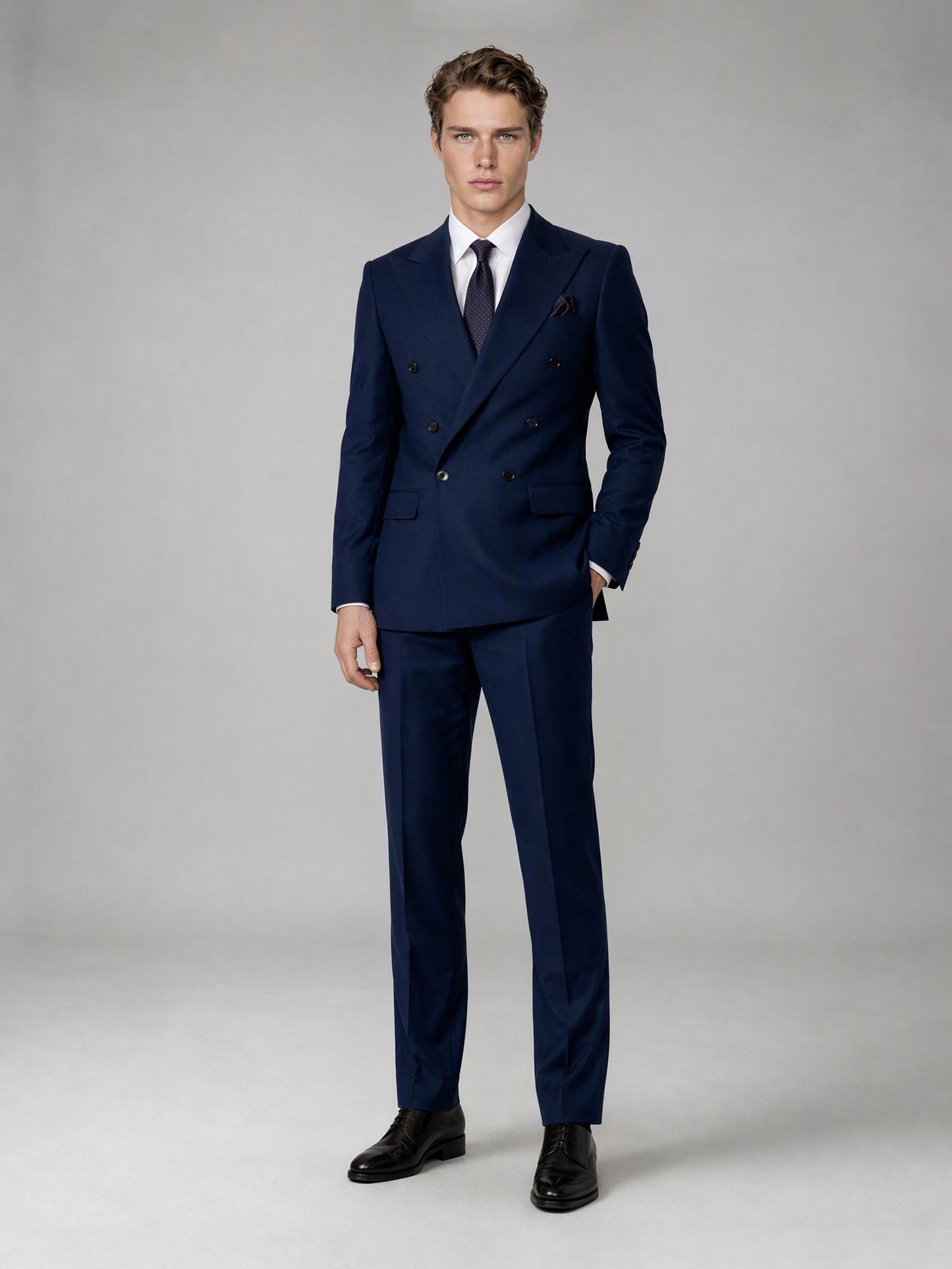 Savile deep navy double-breasted suit – full-length front view, hands in pockets showing complete slim fit silhouette and black brogue oxfords