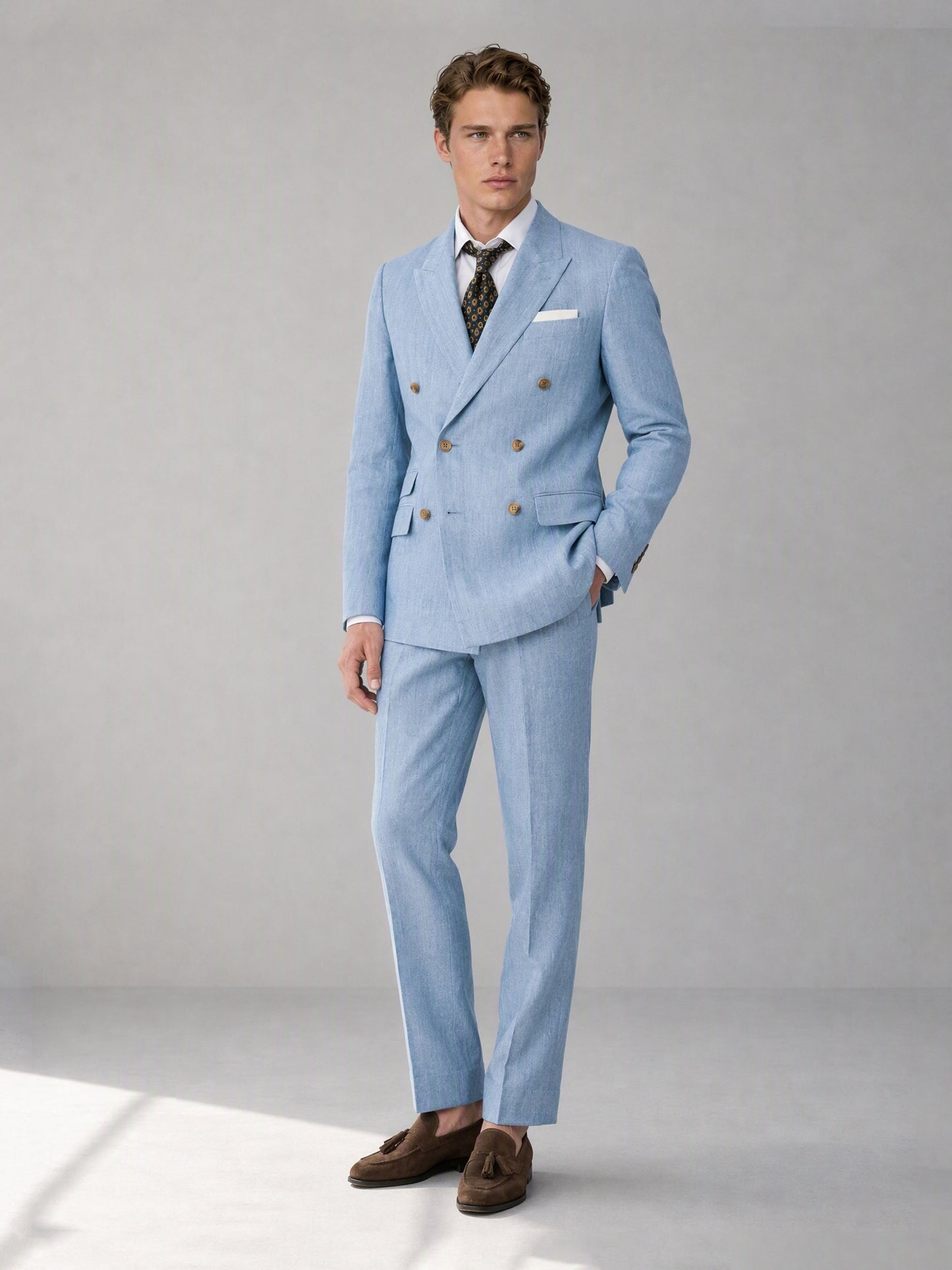 Savile sky blue linen double-breasted suit – close-up face and lapel, gold-tone buttons and linen texture detail with dark floral medallion tie