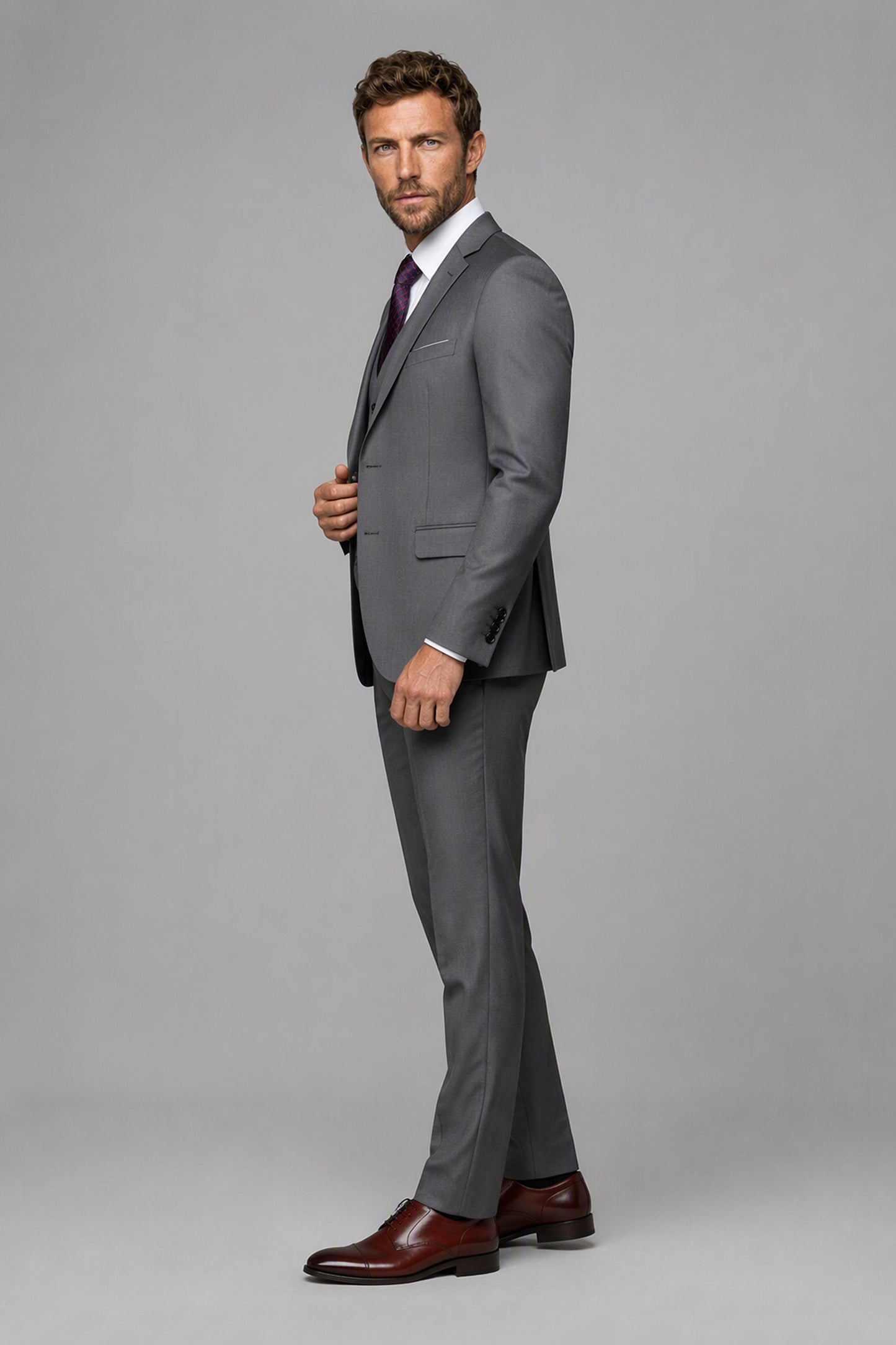Savile Grey 3-Piece Suit Set – Three-quarter side view, model adjusting jacket showing lapel profile and structured shoulder