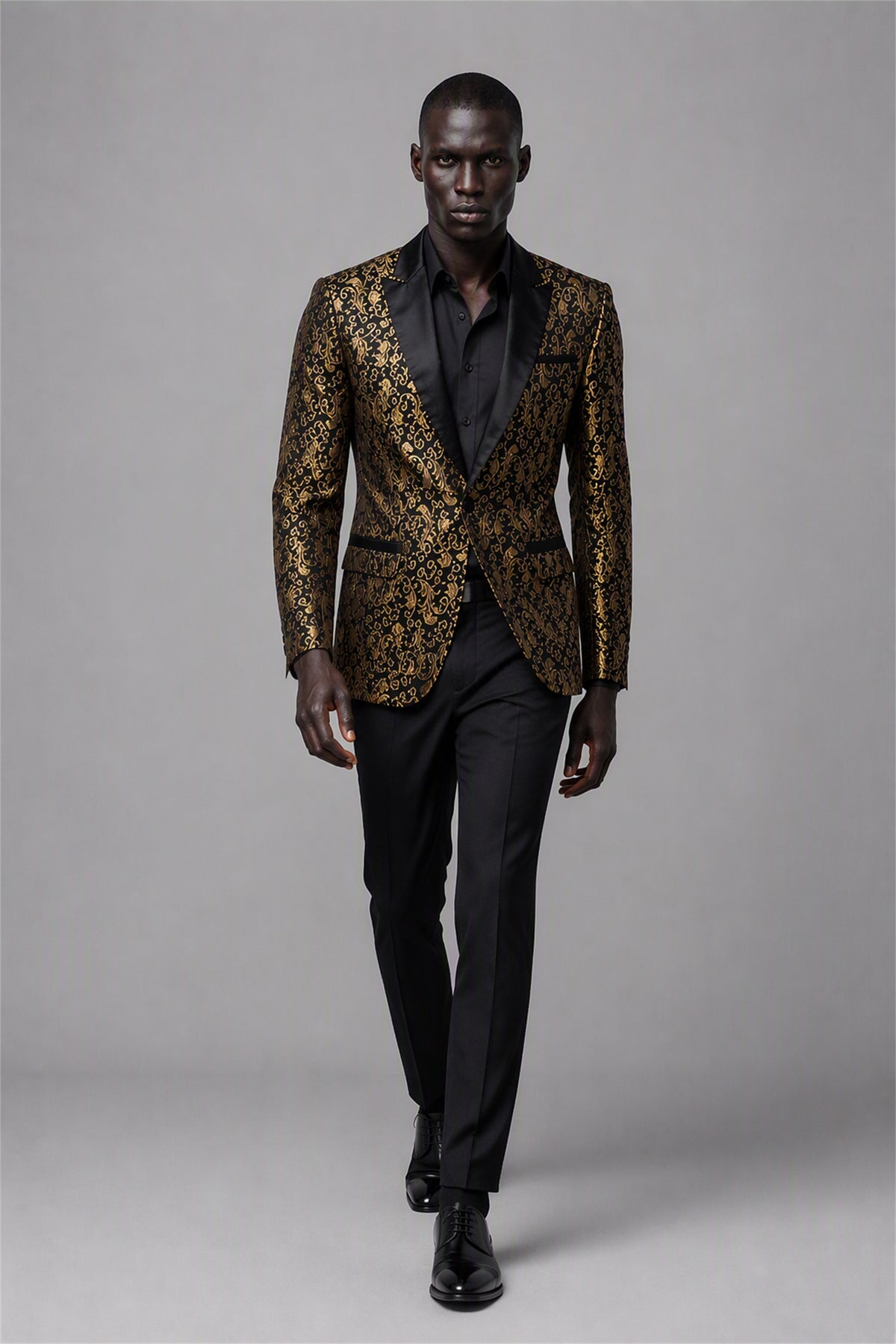 Savile Black & Gold Jacquard Tuxedo Jacket – Full front standing view, hands clasped showing slim-fit silhouette with black shirt and black trousers