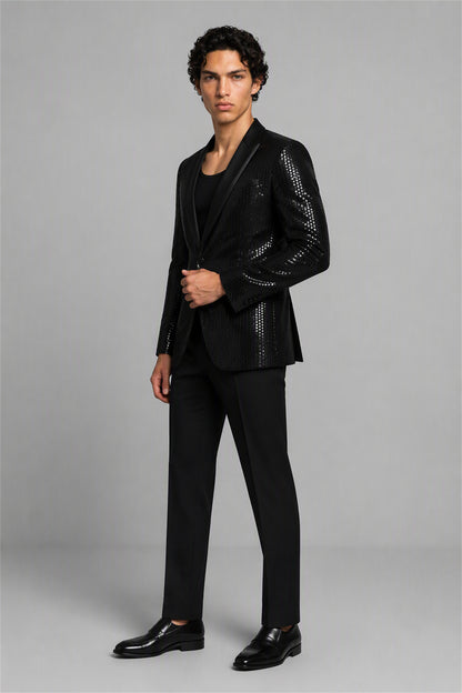 Savile Black Sequin Tuxedo Jacket – Three-quarter front standing view, hand on button showing sequin embellishment and peak lapel contrast