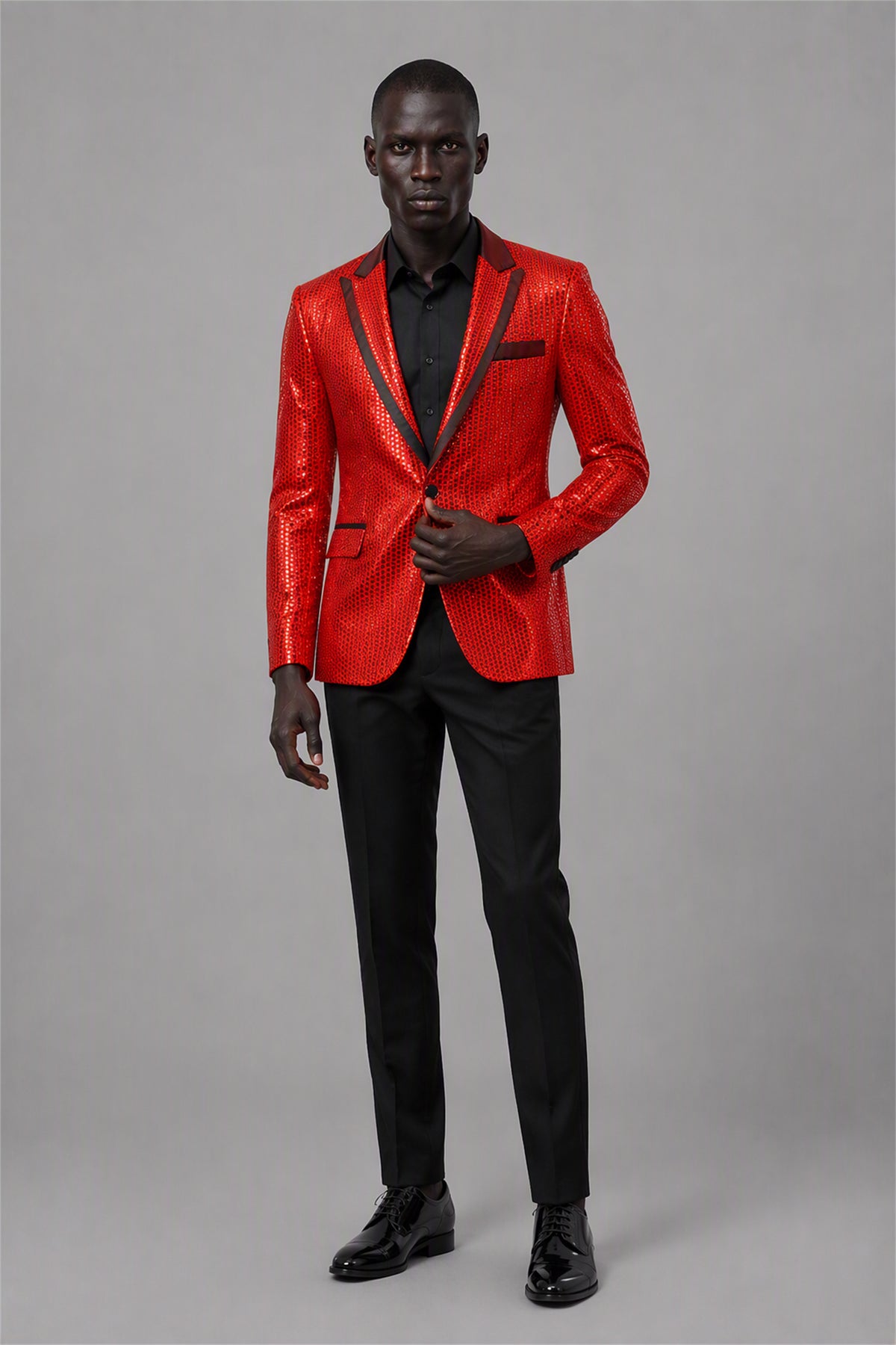 Savile Red Sequin Tuxedo Jacket – Full front walking view showing all-over red sequin jacket with black satin peak lapel, black shirt and black trousers