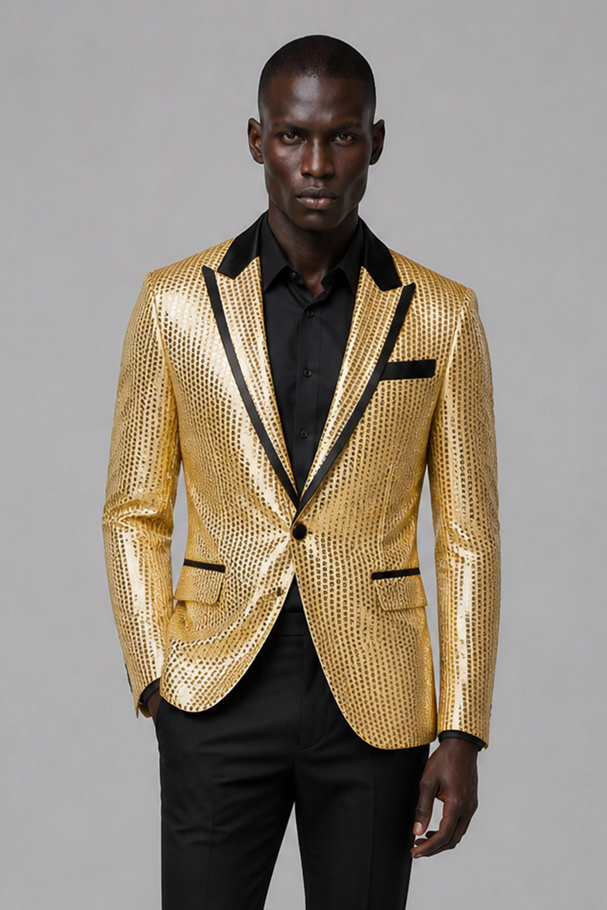 Savile Gold Sequin Tuxedo Jacket – Three-quarter front view, hand on jacket showing gold sequin texture and black satin peak lapel detail