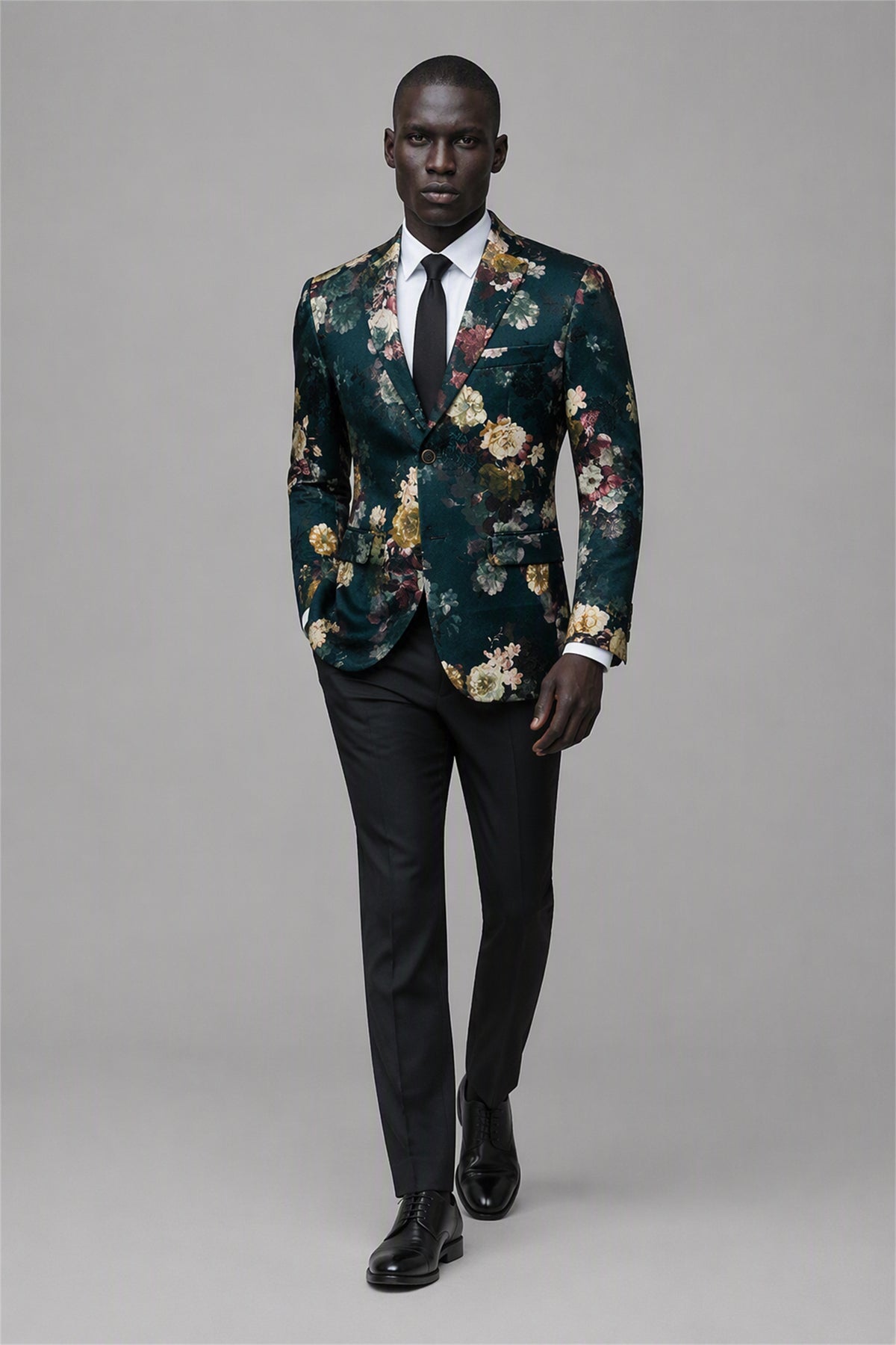 Savile Emerald Green Floral Jacquard Blazer – Full front walking view with white shirt and black tie showing emerald green botanical floral pattern, black notch lapel and black trousers