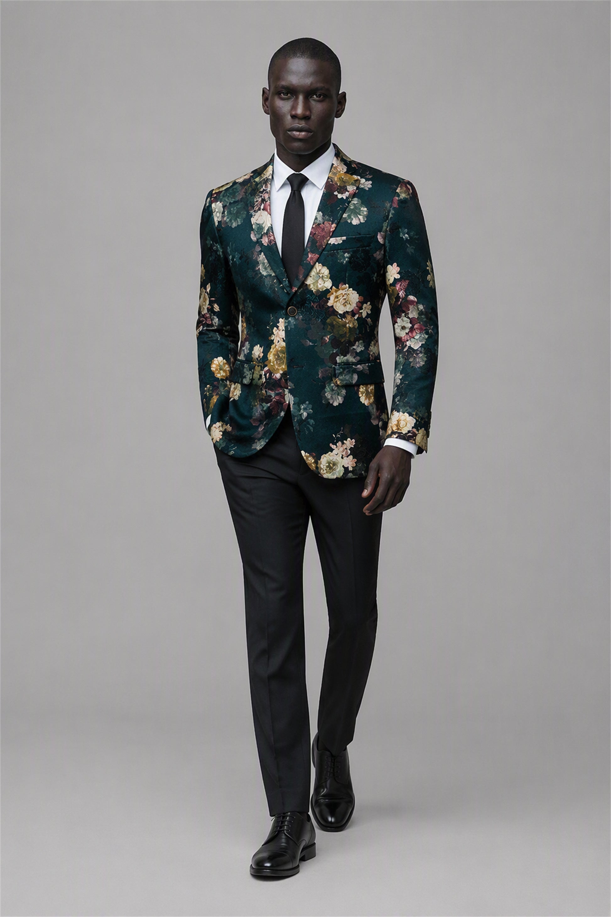 Savile Emerald Green Floral Jacquard Blazer – Full front walking view with white shirt and black tie showing emerald green botanical floral pattern, black notch lapel and black trousers
